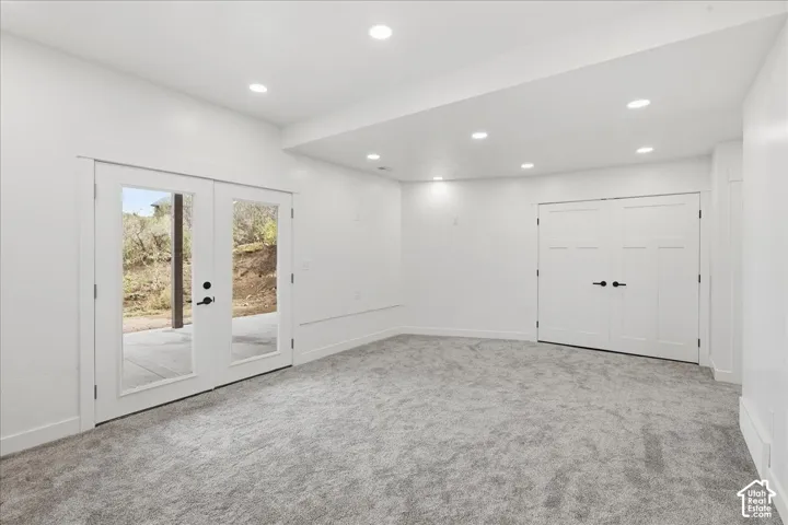 Recessed lighting, light-toned carpeting, white walls, double French doors with black hardware, and double paneled doors with black hardware