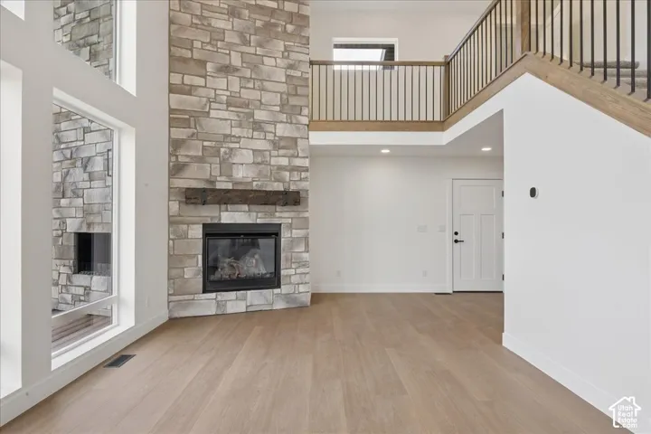 Vaulted ceilings featuring a floor-to-ceiling stone fireplace with a wood mantle