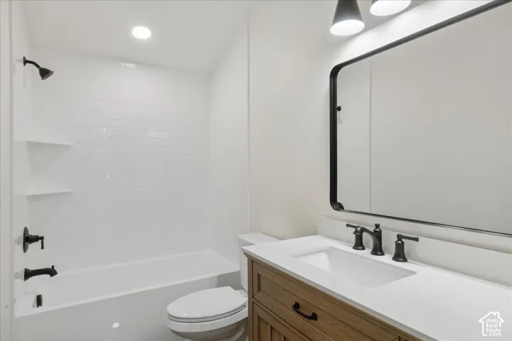 White subway tile shower surround with integrated shelving, matte black fixtures, wood-finish vanity with an integrated sink, and a framed mirror