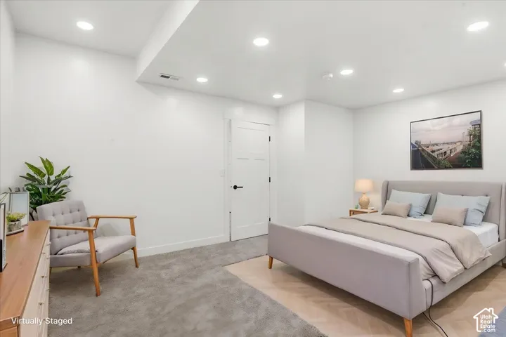 Primary Bedroom. Recessed lighting illuminating a spacious room with light-toned carpet and a white door with black hardware