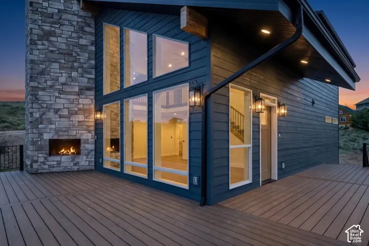 Expansive exterior deck with a stone-clad fireplace and large windows
