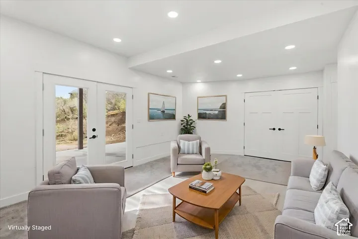 Recessed lighting, light-toned carpeting, double French doors with clear glass, double panel doors with black hardware, and white wall finishes