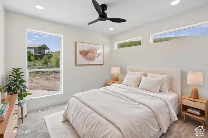 Recessed lighting, a black ceiling fan, and multiple windows illuminate this room