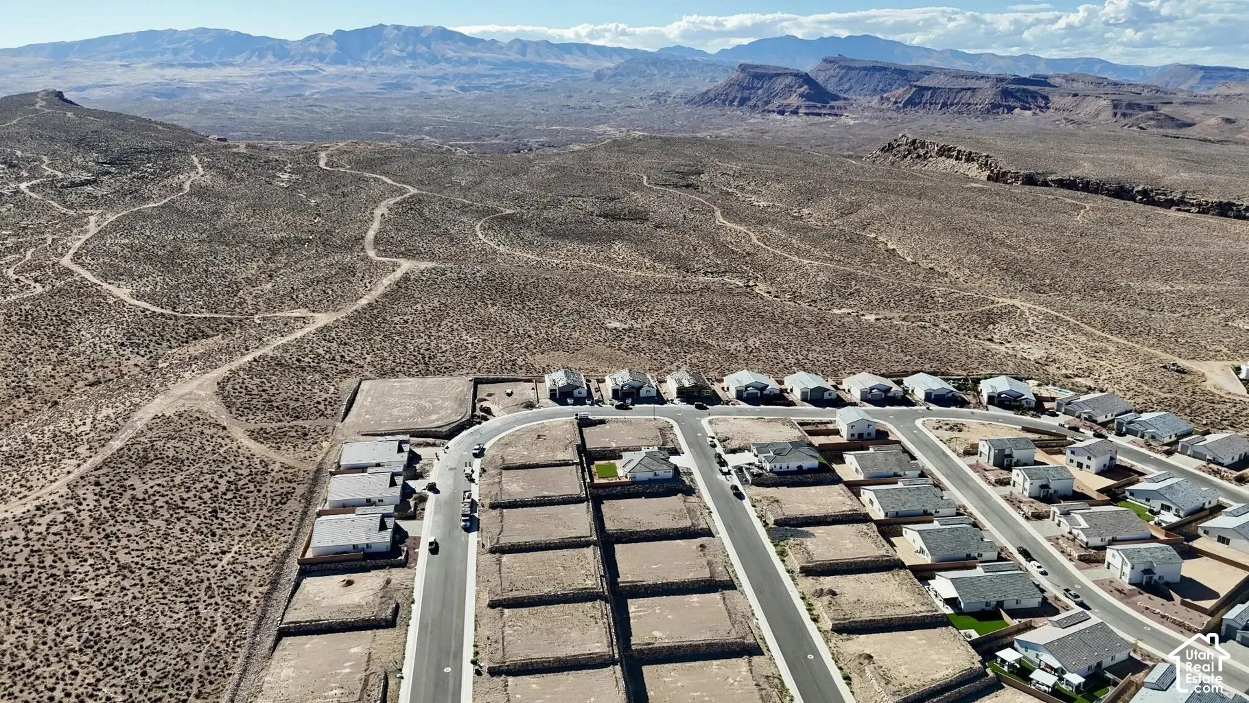 Expansive desert landscape surrounding a developing residential area with paved streets and graded lots