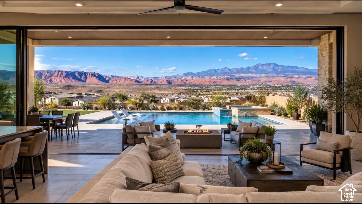 Expansive indoor-outdoor living space with large format tile flooring, a built-in outdoor kitchen, a swimming pool, and a spa with mountain scenery
