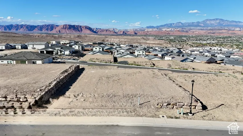 Graded building lot featuring a retaining wall, a paved street, and a community street lamp