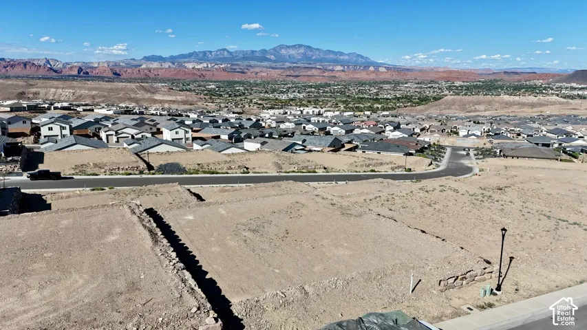 Expansive desert landscape with distant mountains and a residential community