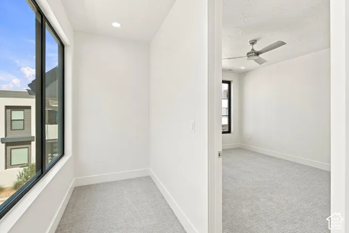 Expansive window with black framing, recessed ceiling lighting, and light-toned carpeting