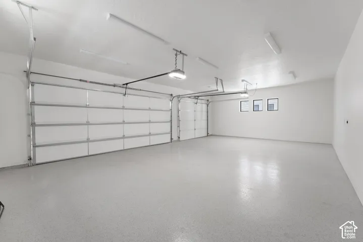 Spacious two-car garage with an epoxy-coated floor, overhead lighting, and dedicated wall windows
