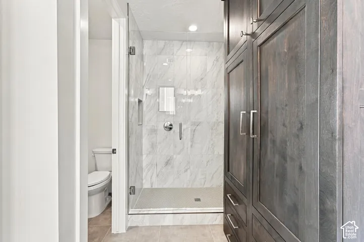 Glass-enclosed shower with marble-finish tile surround and mosaic tile floor