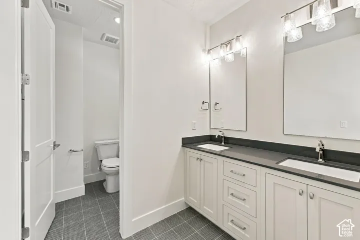 Dual vanity with white cabinetry and dark countertops