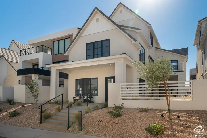 Contemporary exterior featuring a stucco facade, multiple balconies, a covered entryway, and a tiered xeriscape garden with steps
