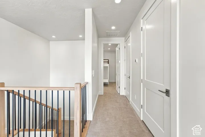 Carpeted hallway featuring recessed lighting and multiple white paneled doors