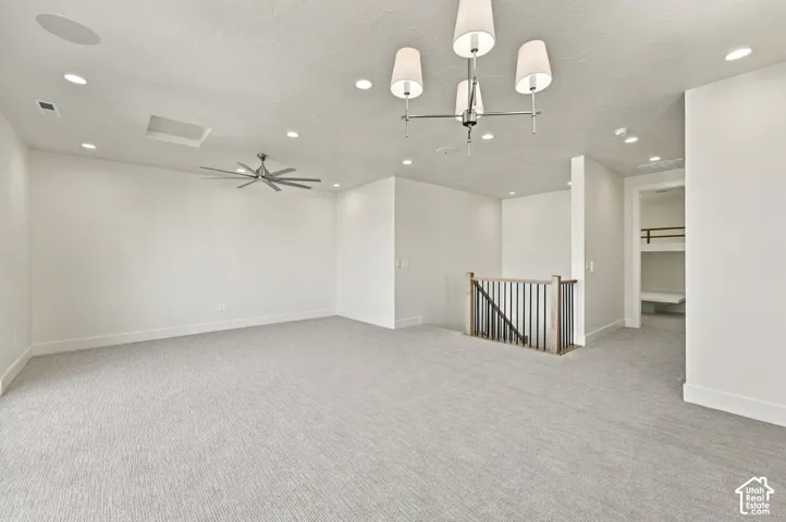 Spacious carpeted room featuring recessed lighting, a ceiling fan, and a contemporary chandelier