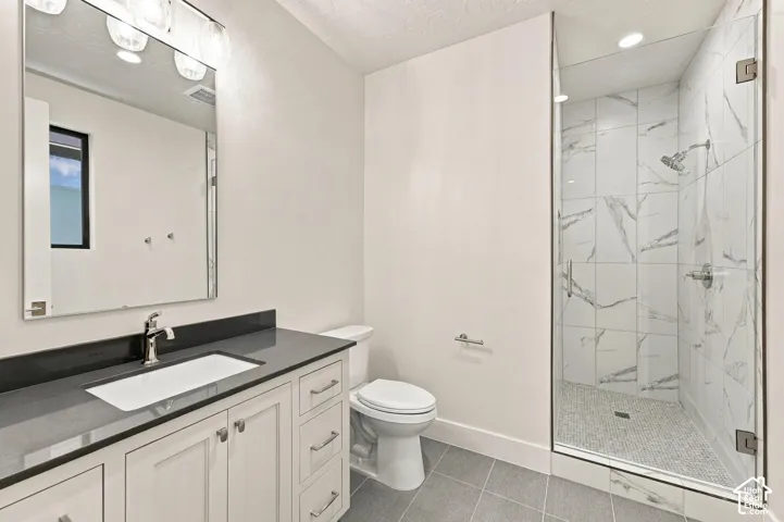 White vanity with dark countertop, large framed mirror, and chrome fixtures