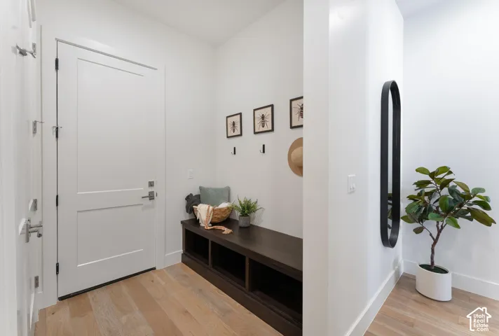 Light wood-finish flooring, white walls, built-in dark wood-finish bench with open shelving, and a modern black-framed mirror
