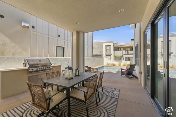 Covered patio with an outdoor kitchen, integrated grill, and built-in cabinetry