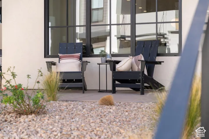 Stucco exterior with large grid-pattern windows, a concrete patio, and a gravel landscape