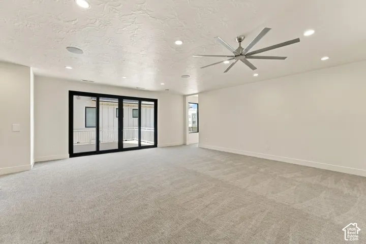 Spacious room with light-toned carpet flooring, recessed lighting, and a contemporary ceiling fan
