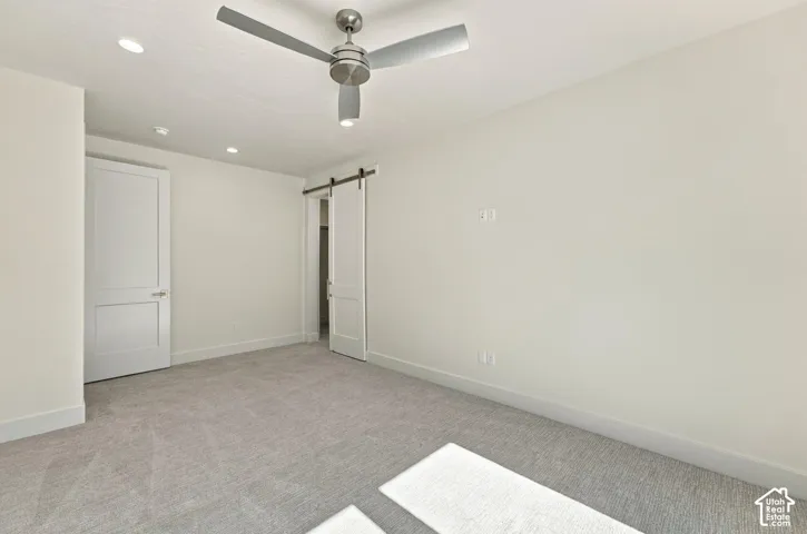 Recessed lighting, ceiling fan with brushed nickel finish, two-panel interior door, barn door entry, and light gray carpeting