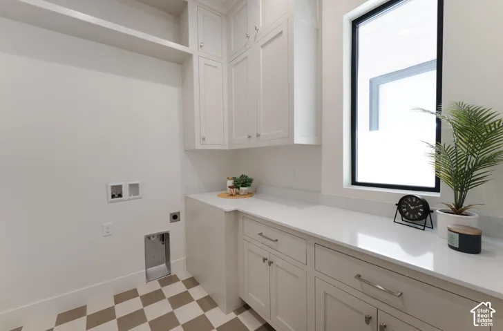White shaker cabinetry with polished chrome hardware, light-toned countertop, a rectangular window with black trim, and checkerboard floor tiles