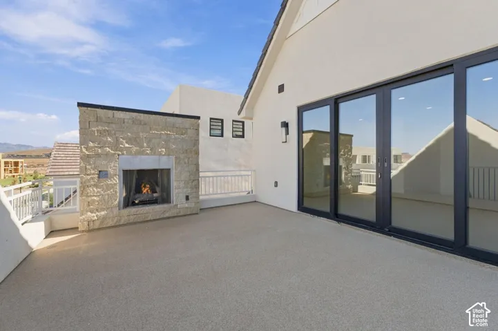 Expansive outdoor deck with a stone-clad fireplace and large sliding glass doors