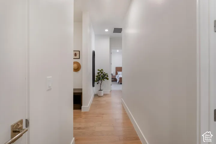 Hallway featuring recessed lighting, wood-finish flooring, and crisp white walls