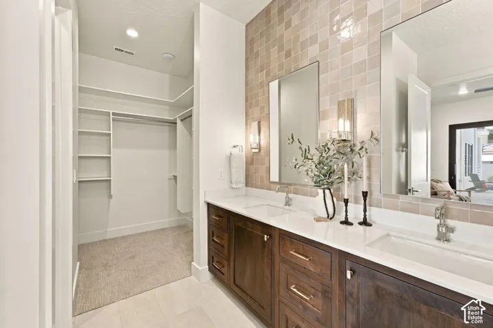 Dual vanities with white countertops, wood-finish cabinetry, and contemporary lighting