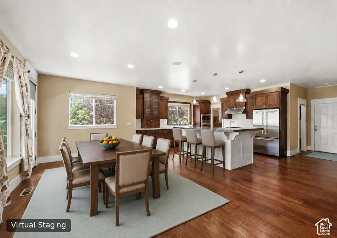 Hardwood flooring, recessed lighting, wood cabinetry, stainless steel appliances, and a kitchen island with seating