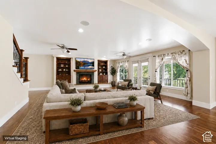 Expansive living area with wood-finish flooring, a stone-clad fireplace with a wood mantle, and built-in shelving