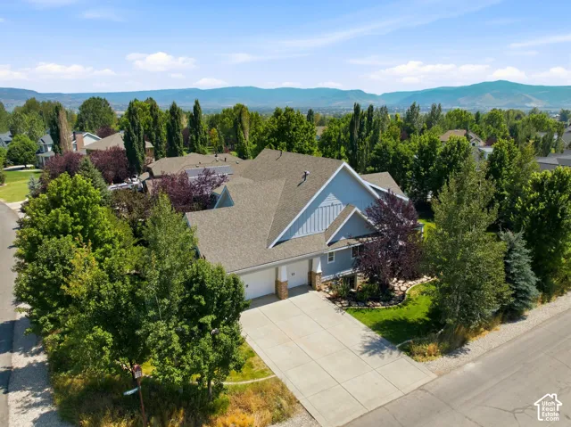 Property featuring a two-car garage, concrete driveway, and mature landscaping