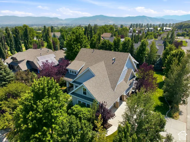 Gabled roofline, light blue siding, stone facade accents, mature landscaping, and an asphalt driveway