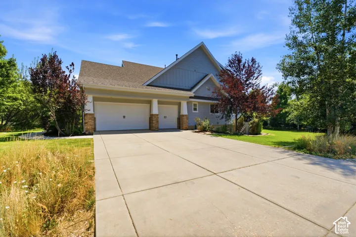 Exterior featuring light blue siding, a two-car garage with white doors, and stone column accents
