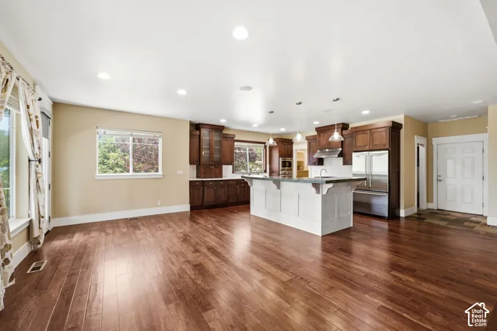 Open-concept living area with wood-finish flooring, recessed lighting, and multiple windows
