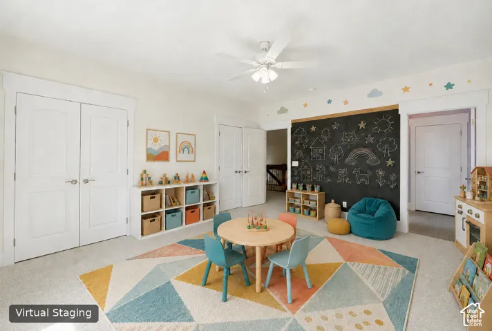 Carpeted room featuring a built-in chalkboard wall, multiple panel doors with brushed nickel hardware, and a ceiling fan