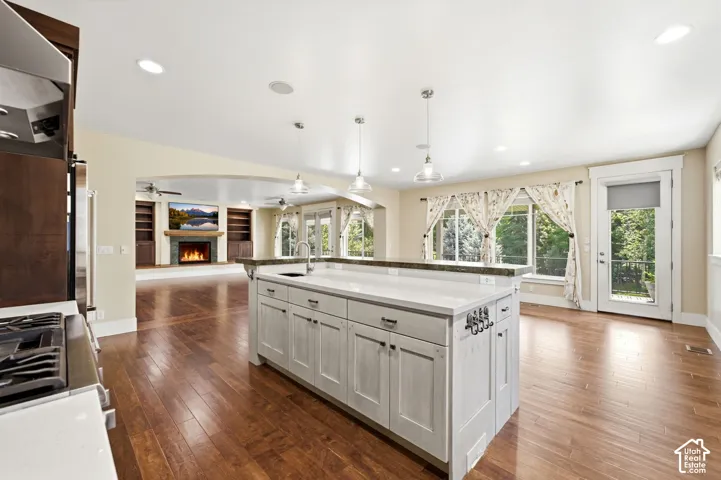 Kitchen island with white shaker-style cabinetry and a light-toned countertop, featuring a sink and pendant lighting
