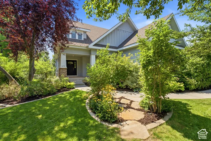 Traditional-style home with a covered entry, stone column accents, and a dark paneled front door