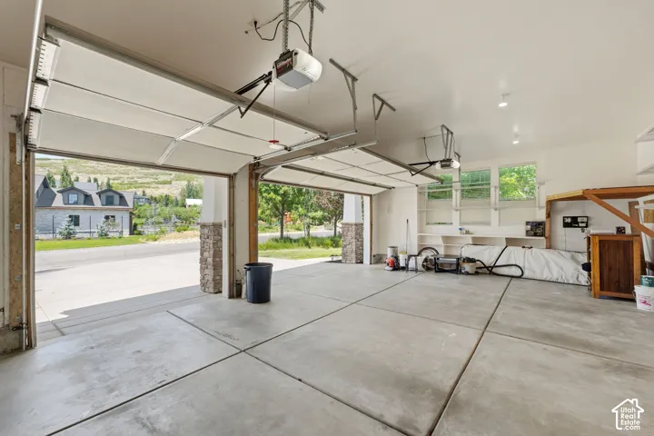 Concrete flooring, built-in shelving, recessed lighting, double garage doors, stone-clad garage door pillars