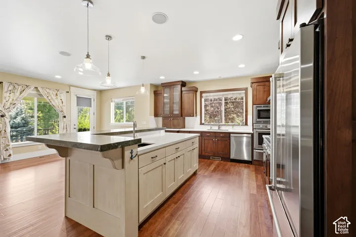 Hardwood flooring throughout, large central island with integrated sink, stainless steel appliances, recessed lighting, and ample natural light from multiple windows