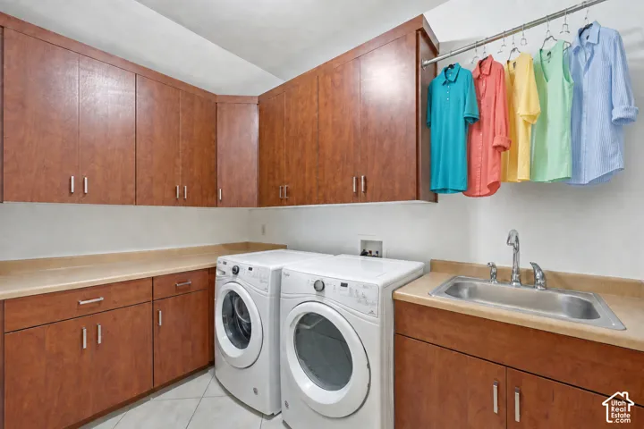 Laundry area featuring extensive wood-finish cabinetry, a utility sink with a chrome faucet, and ample countertop space