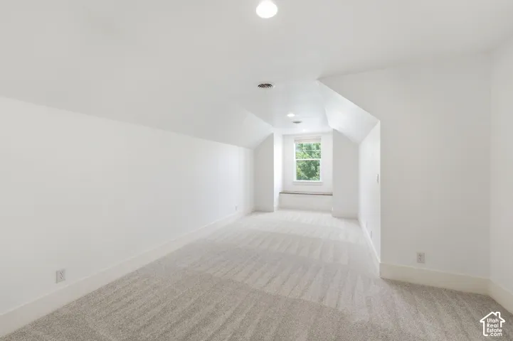 Recessed lighting, sloped ceilings, window seat, and neutral carpeting
