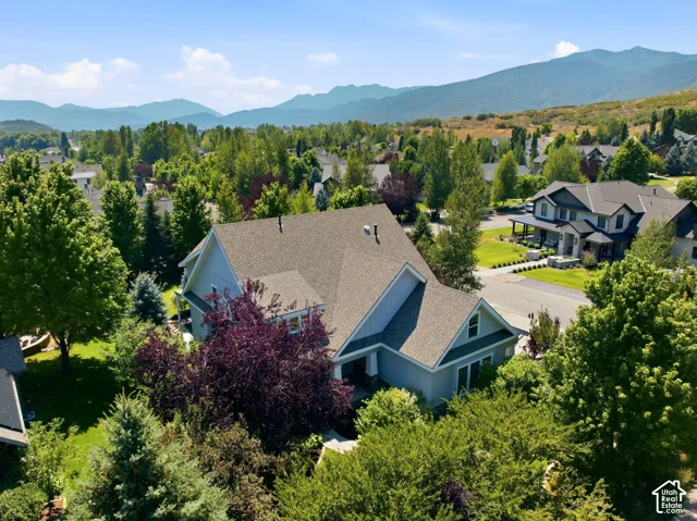 Light blue siding exterior with a multi-level roofline, surrounded by mature trees and varied landscaping