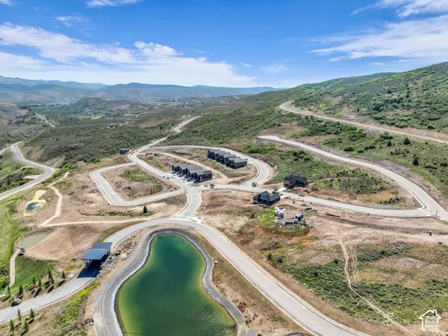 Mountainous landscape with an artificial pond, paved roads, and residential structures