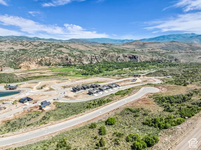 Expansive land offering development opportunities, featuring several structures in various stages of completion, roads, and a water feature