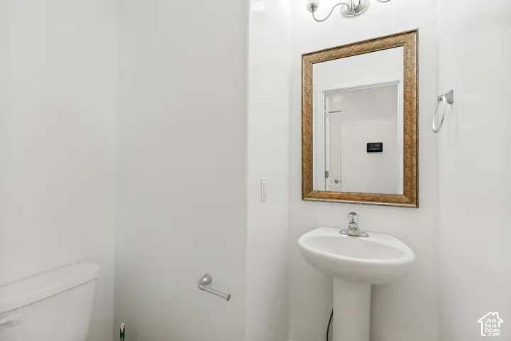Pedestal sink with chrome faucet, framed mirror, and wall-mounted light fixture
