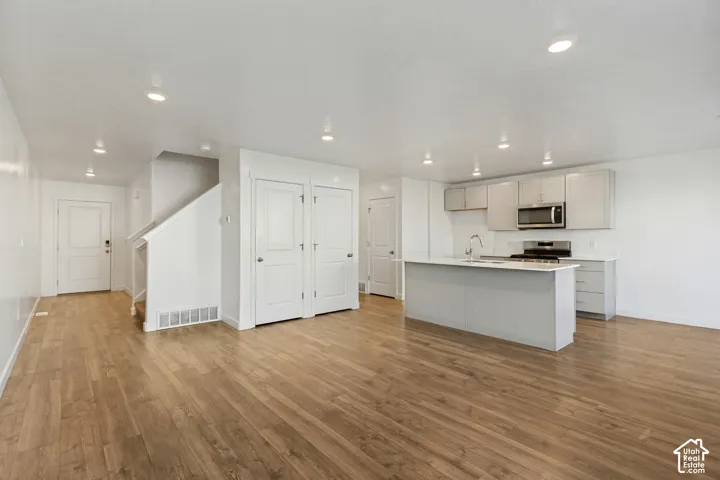 Wood-finish flooring, recessed lighting, and a kitchen island with sink