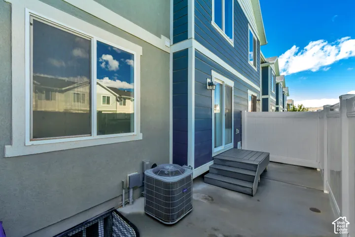 Outdoor patio space featuring a privacy fence, concrete surface, and a multi-level deck leading to a sliding glass door
