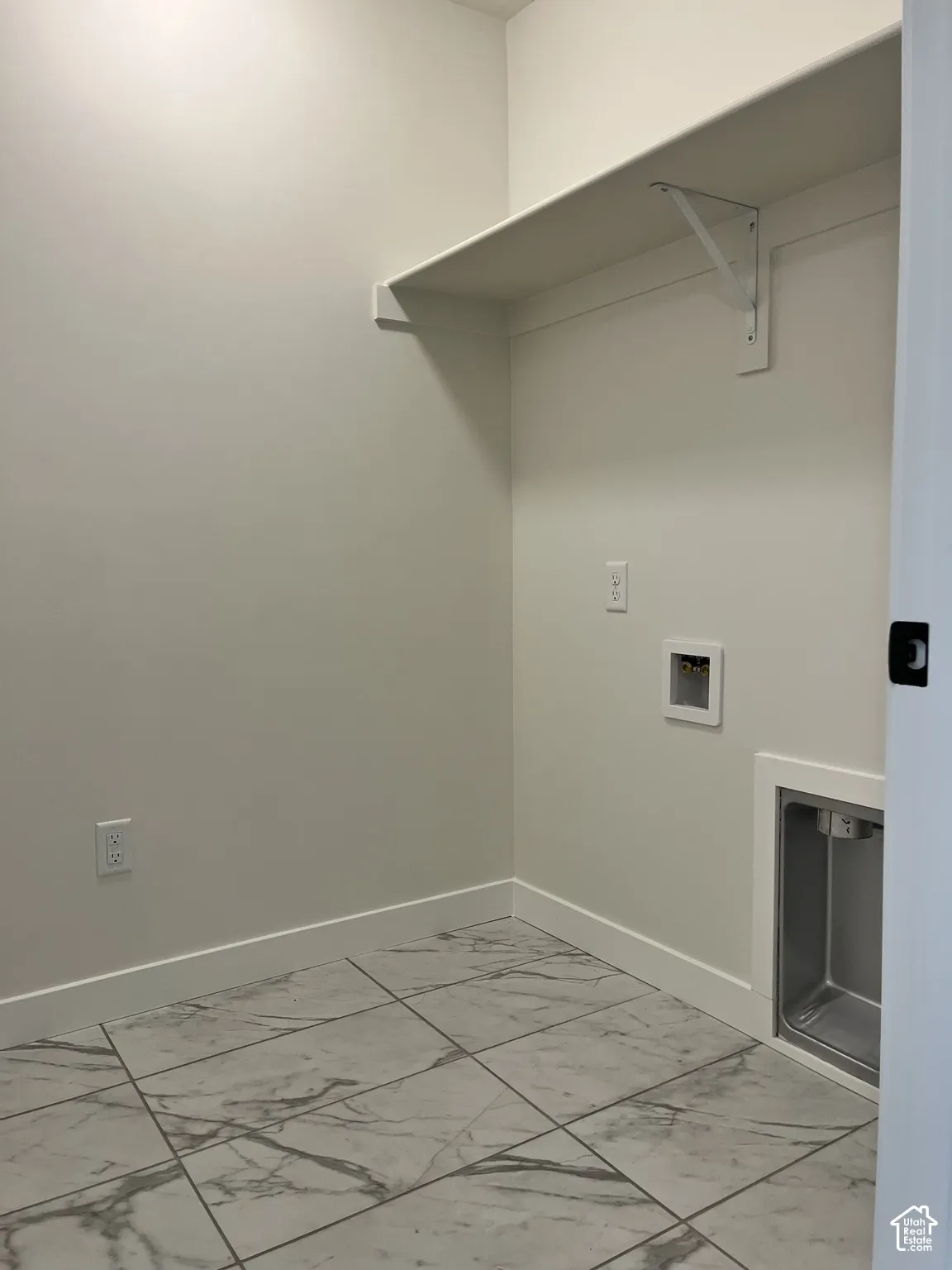 Built-in shelving, utility hookups, and a laundry basin complement the tile flooring