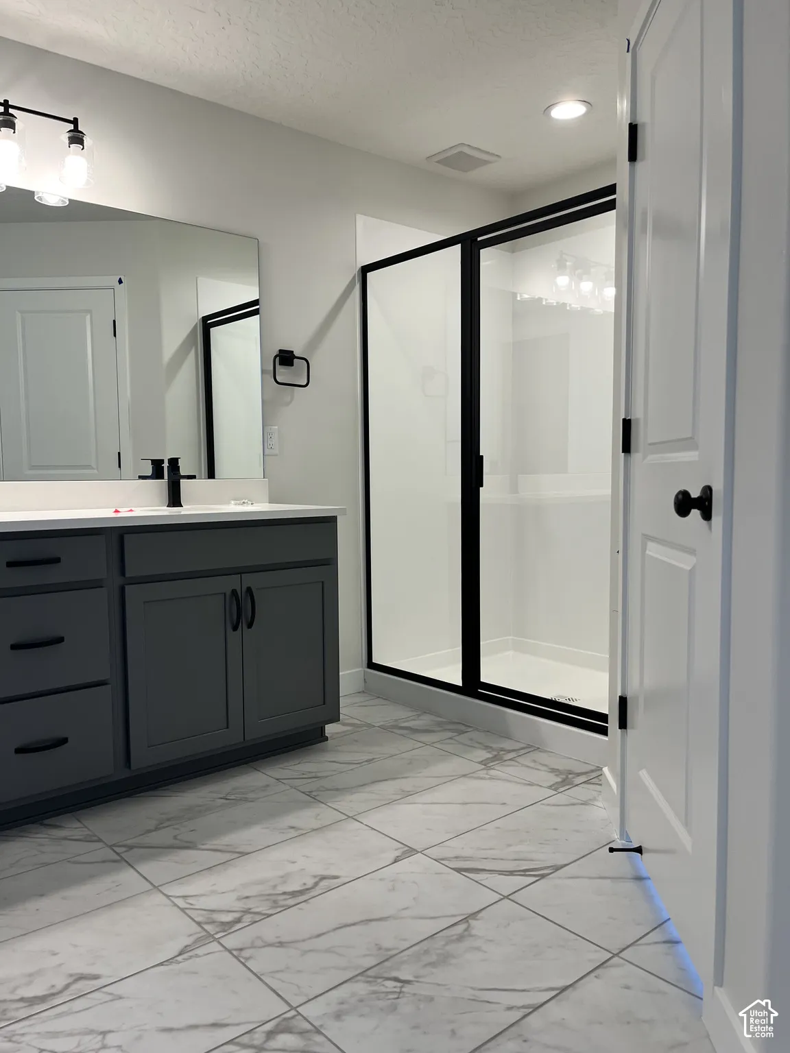 Vanity with a quartz countertop, modern black fixtures, and a large wall-mounted mirror