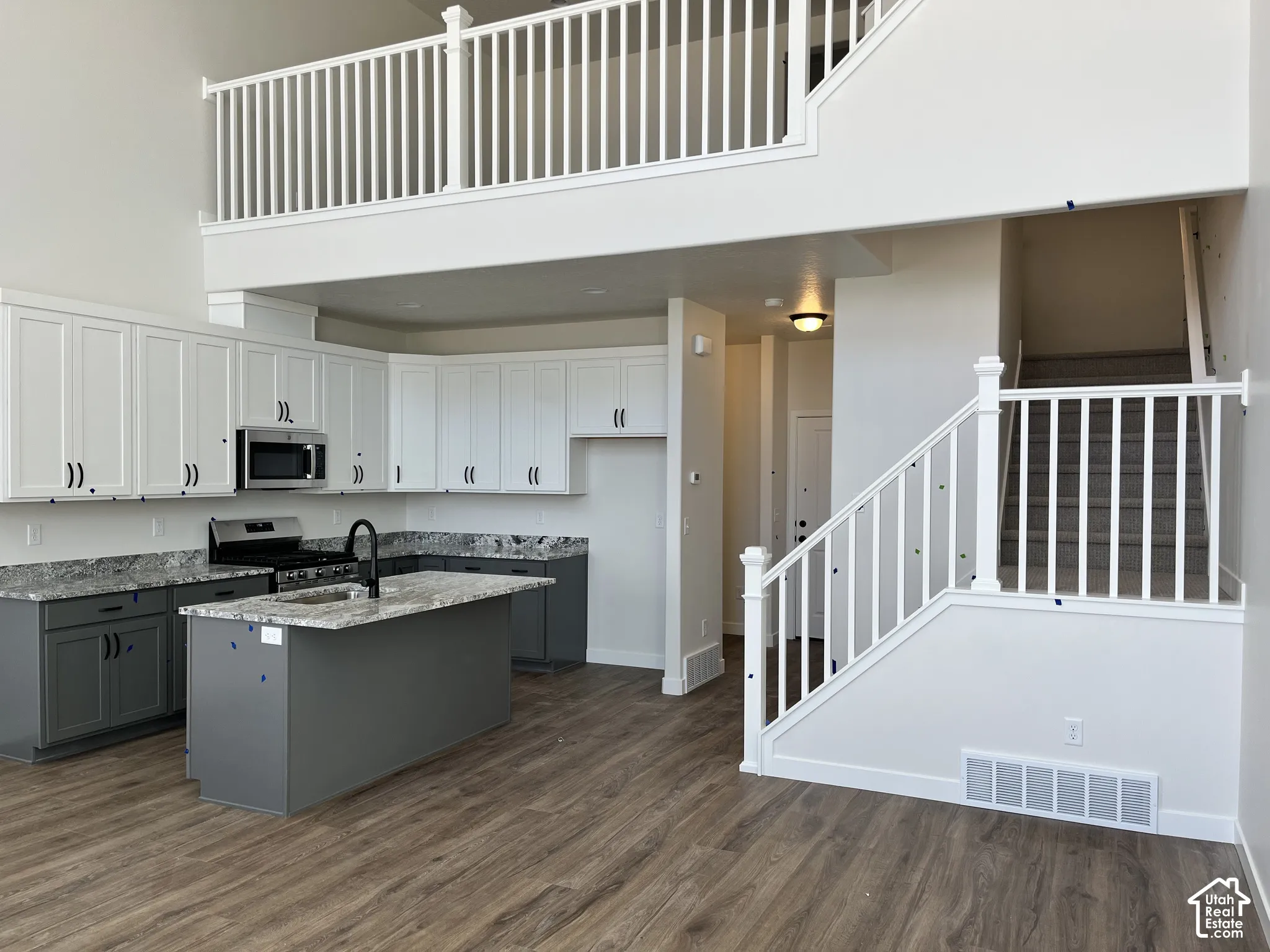 Spacious kitchen featuring two-tone cabinetry, stainless steel appliances, and a central island with a sink